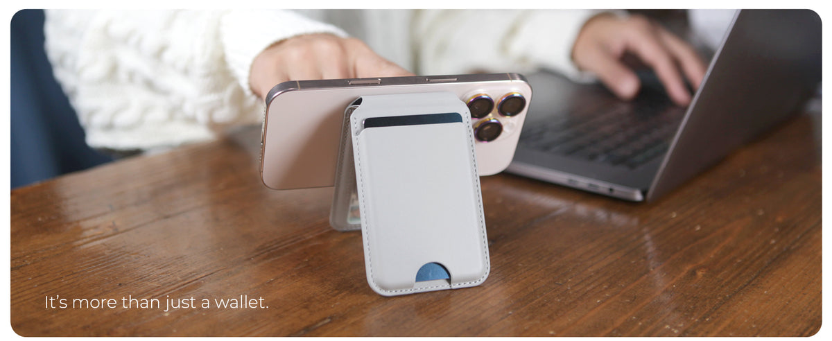 Wallet stand holding an iPhone upright on a desk next to a laptop